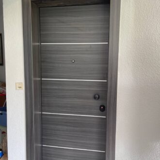 Door Θωρακισμένη πόρτα σε ανθρακί απόχρωση με ίνοξ και μαύρες λεπτομέρειες, κατασκευασμένη από το επιπλοποιείο μας Wood Design Πάτσης στην Πτολεμαΐδα.