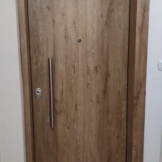 Porta 3 Θωρακισμένη πόρτα, σε δρυς απόχρωση με ίνοξ λεπτομέρειες, κατασκευασμένη από το επιπλοποιείο μας Wood Design Πάτσης στην Πτολεμαΐδα.