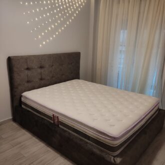 Διπλό κρεβάτι σε σκούρο γκρι χρώμα με καπιτονέ ύφασμα, κατασκευασμένο από το επιπλοποιείο μας Wood Design Πάτσης στην Πτολεμαΐδα.