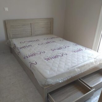 Διπλό κρεβάτι σε ανοιχτό γκρι χρώμα με συρταράκια, κατασκευασμένο από το επιπλοποιείο μας Wood Design Πάτσης στην Πτολεμαΐδα.